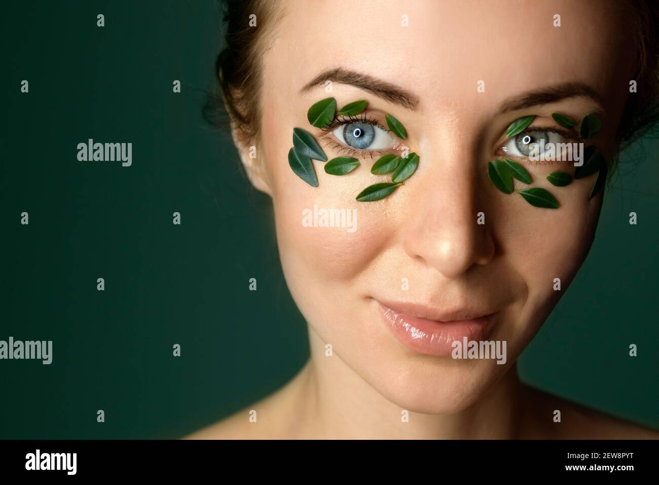 Closeup of young woman`s face with boxwood leaf patches. Spa and wellness concept template banner for design. Cosmetic product advertising Stock Photo